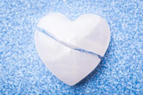Broken apart stone in shape of a heart on blue background Stock Photos