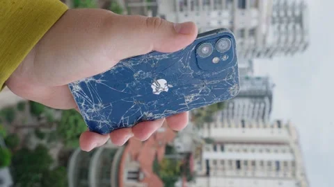 Broken Apple iPhone in hand on the background of the city, vertical video Stock Footage 229802059