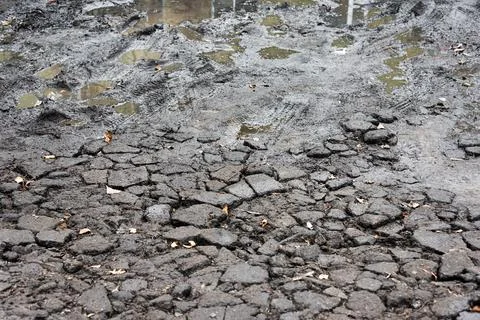 Broken asphalt with dirt. Bad bumpy road with potholes, destroyed asphalt and Stock Photos