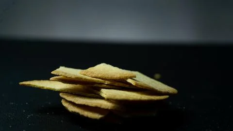 Broken baked chips on a black table background Stock Photos