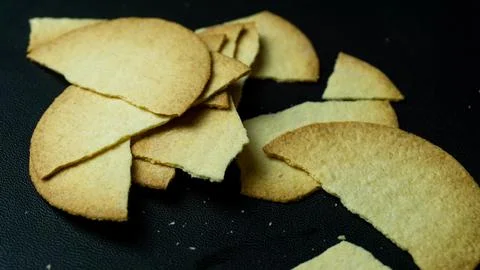 Broken baked chips crisps isolated on black background Stock Photos