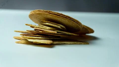 Broken baked chips crisps on a white table background Stock Photos