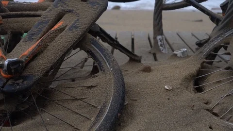 Broken bikes on the beach, covered in sand during a storm Stock Footage 123385016