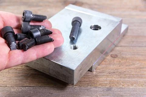 Broken black bolts in worker's hand. Bolt with a hexagonal head. Stock Photos