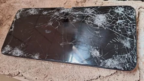 Broken black smartphone screen with many deep cracks and fractures Stock Photos