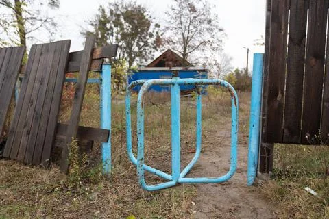Broken blue barrier marks an empty path near a house in an overgrown area d.. Stock Photos