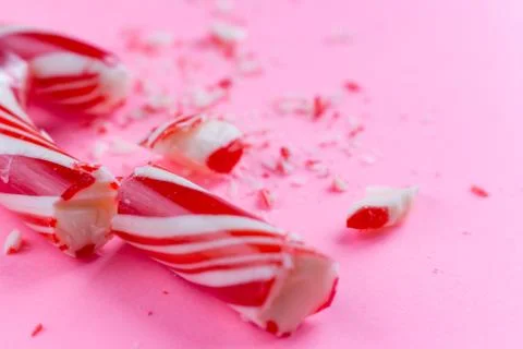 Broken candy cane on pink background. close-up photo Stock Photos