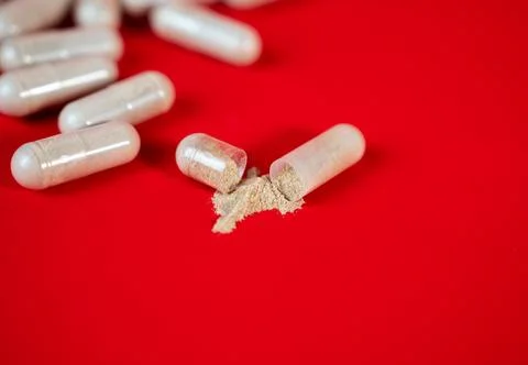 Broken capsule with powder on red background Stock Photos