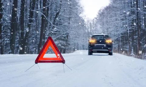 Broken car and warning triangle on the snowy winter road Stock Photos