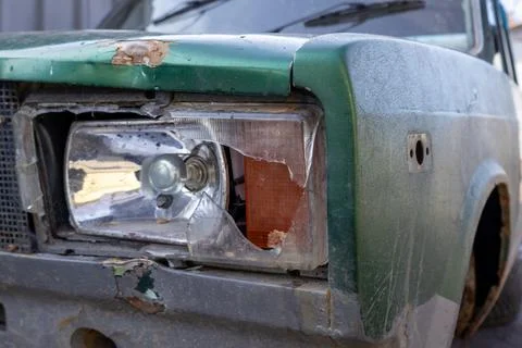 A broken car headlight is seen on an old vehicle parked at a repair shop in.. 스톡 사진