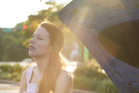 Broken car on a road. Side view of a young stressed woman driver Stock Photos