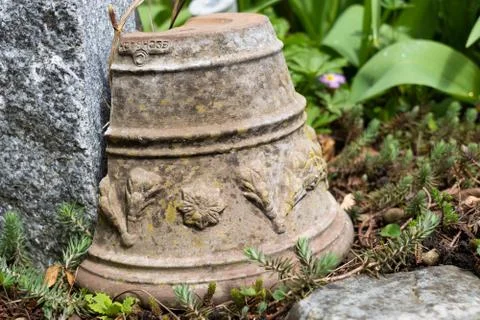 Broken ceramic plant pot with ornamental sculptures on ground of flowerbed. Stock Photos