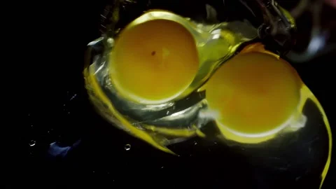 A broken chicken egg falls in slow motion. Footage shot on a black isolated Stock Footage 148357083