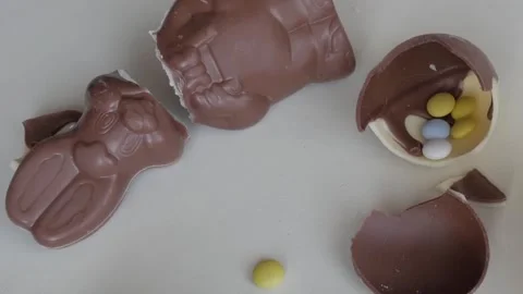 Broken Chocolate Easter Bunnies with Candy Eggs on White Tabletop Stock Footage 333111423