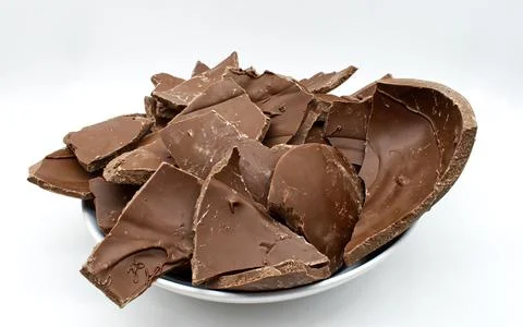 Broken chocolate easter egg in a bowl isolated on white background Stock Photos