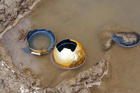 A broken Christmas tree toy in the shape of a ball lies in a muddy puddle. Th Stock Photos