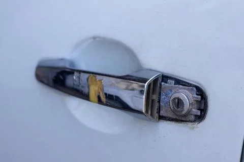 Broken chrome car door handle with exposed key lock cylinder on vehicle body. Stock Photos