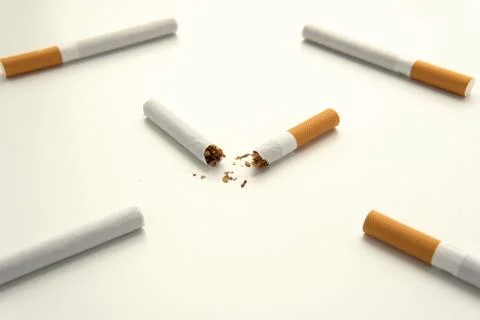 Broken cigarette in half against the background of whole cigarettes Stock Photos