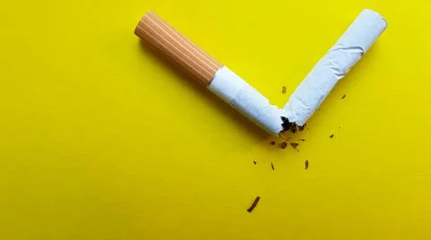 Broken cigarette isolated on a yellow background. View from above Foto stock