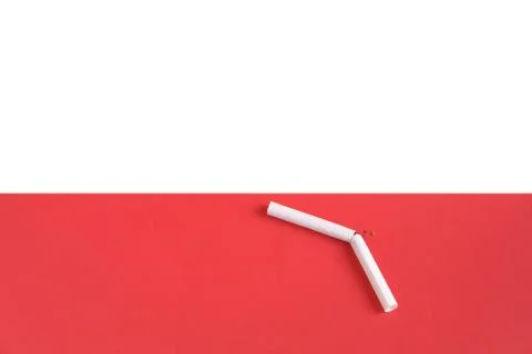 Broken cigarette on a light pink background. Stock Photos