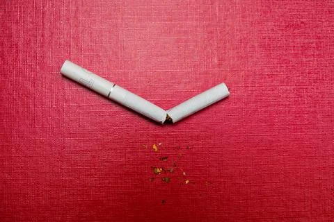 Broken cigarette on a red background. Stock Photos