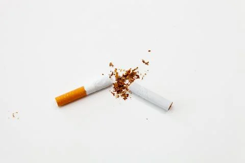 Broken cigarette on a white surface with a filter on the left, top view Stock Photos