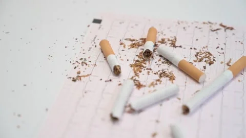 Broken cigarettes falling on electrocardiogram paper Stock Footage 335191967