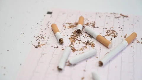 Broken cigarettes falling on electrocardiogram paper Stock Footage 335191974