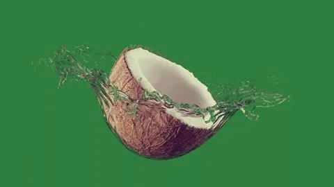 A broken coconut on green background and with water splashing out of it an Video stock 335129748