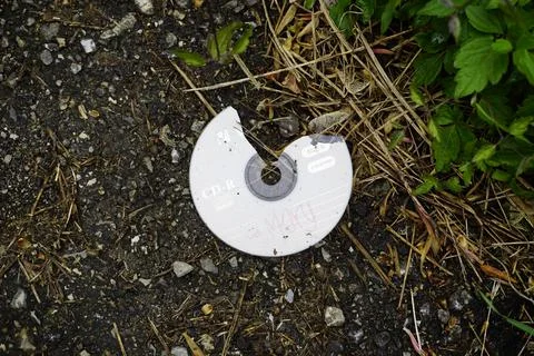 Broken compact disk thrown on the ground Stock Photos