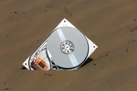 Broken computer hard drive in sand Foto stock
