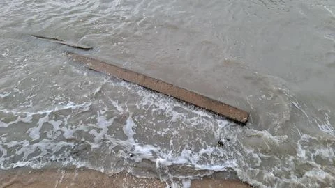 Broken Concrete Beam Washed by Ocean Waves on Sandy Beach Stock Photos
