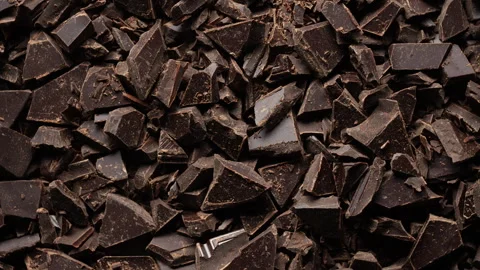 Broken crushed dark chocolate bits on background rotates.  Sweet food 스톡 동영상 318874650