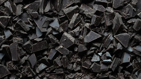 Broken crushed dark chocolate bits on background rotates.  Sweet food 스톡 동영상 319744224