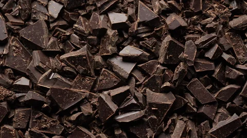 Broken crushed dark chocolate bits on background rotates.  Sweet food Vídeos de archivo 331536976
