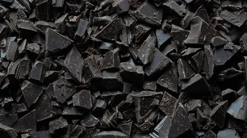 Broken crushed dark chocolate bits on background rotates.  Sweet food 스톡 동영상 332757488