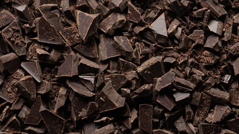 Broken crushed dark chocolate bits on background rotates.  Sweet food 스톡 동영상 334046242
