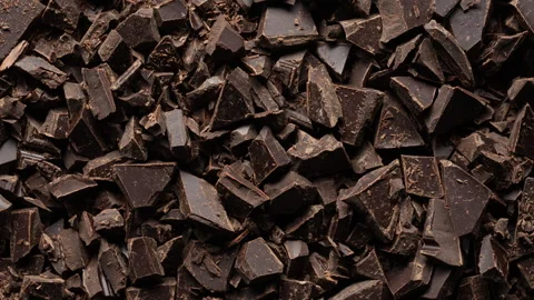 Broken crushed dark chocolate bits on background rotates.  Sweet food Video stock 345708878