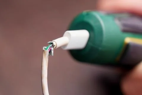 Broken damaged charging cable of cordless screwdriver with exposed wires on d Stock Photos
