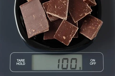 Broken dark chocolate on kitchen scale Stock Photos