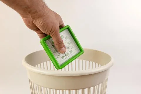 A broken desk clock is thrown into the trash can. Disposal of household waste Stock Photos