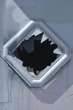 Broken diamond shaped window on weathered wall Stock Photos