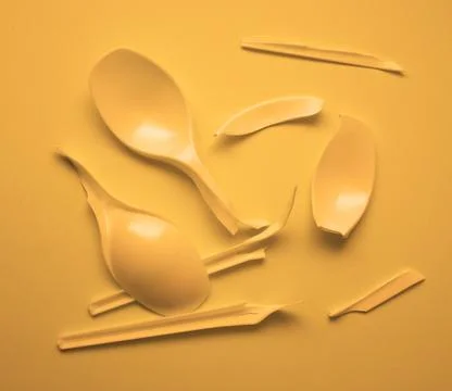 Broken disposable plastic orange spoons. Broken plastic on a orange background Stock Photos