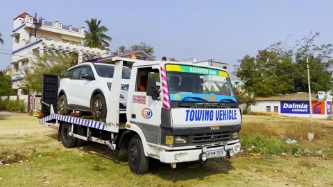 Broken down car on flatbed tow truck being transported to garage workshop for Stock Footage 332423477