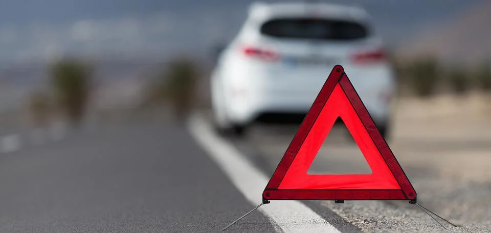 Broken down car with warning triangle behind it waiting for assistance to arrive Stock Photos