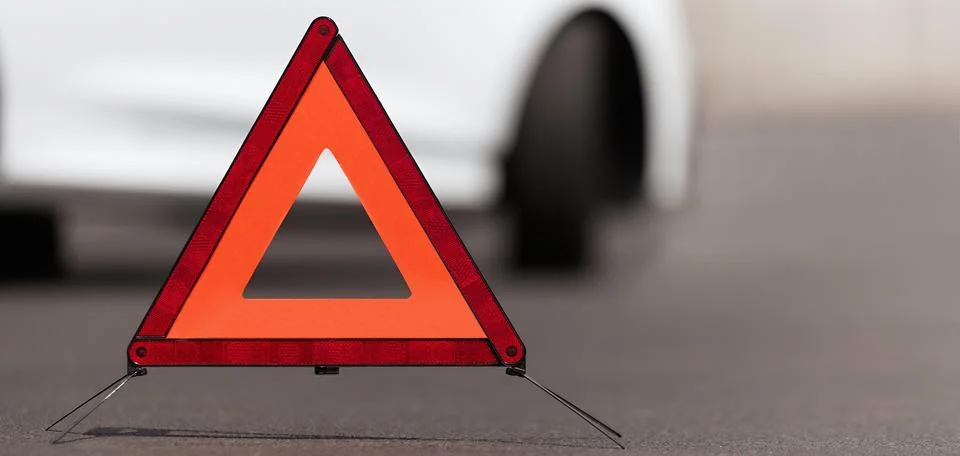 Broken down car with warning triangle behind it waiting for assistance to arrive Stock Photos