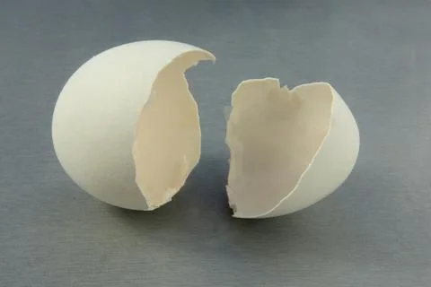 Broken egg close up image. Shell fragments or shatters on gray kitchen table  Stock-Fotos