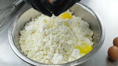 Broken egg falling into bowl with cottage cheese. Video stock 166145599