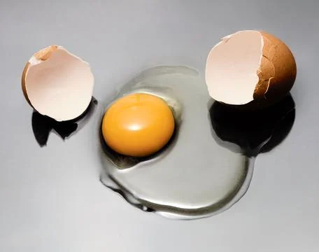 Broken Egg on Glossy Surface Stock Photos