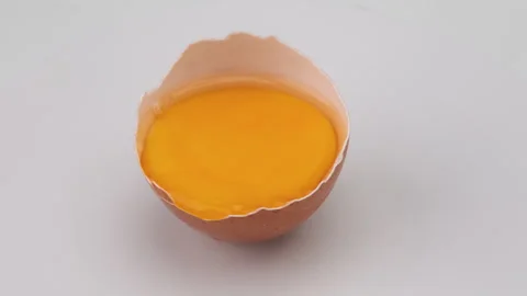 Broken egg in half eggshell is turning on white background. Stock Footage 248435399